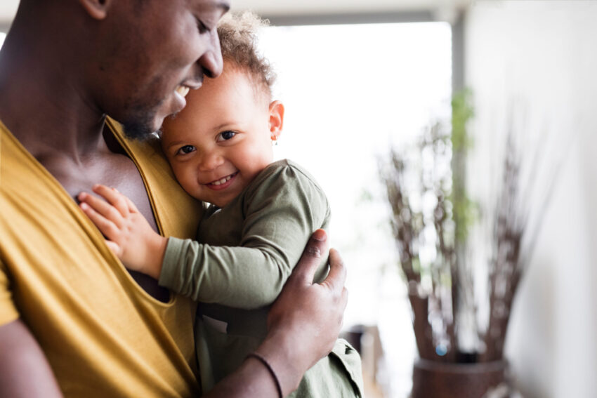 Father holding daughter cuddled, with both smiling
