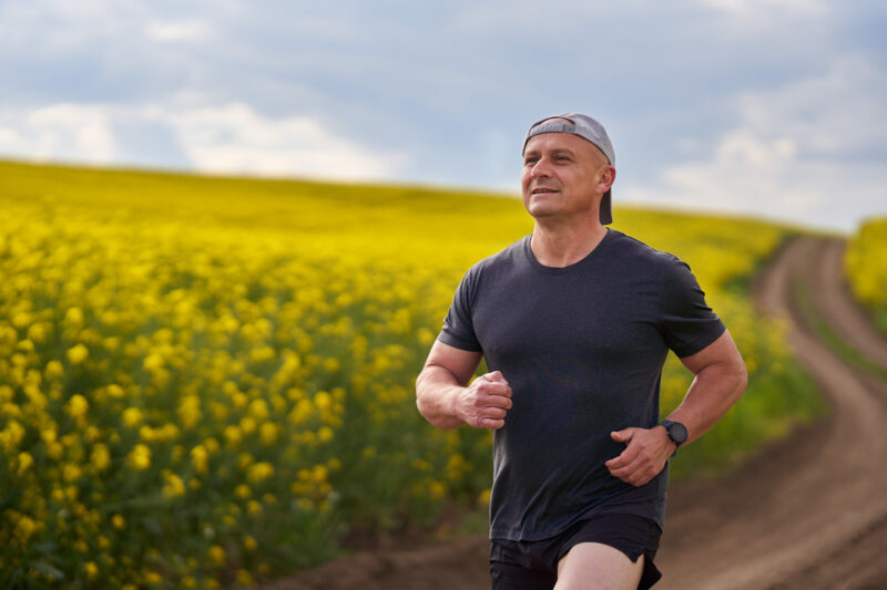 Distance runner running on a road through canola field