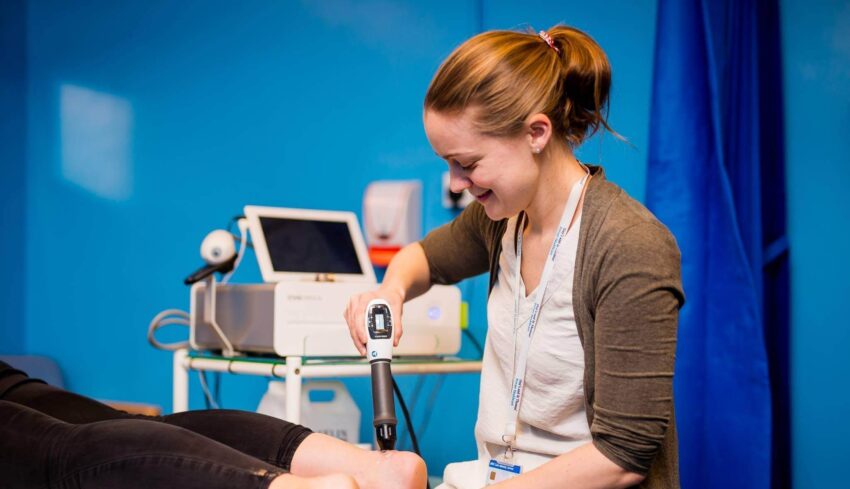 Female physiotherapist performing shockwave therapy